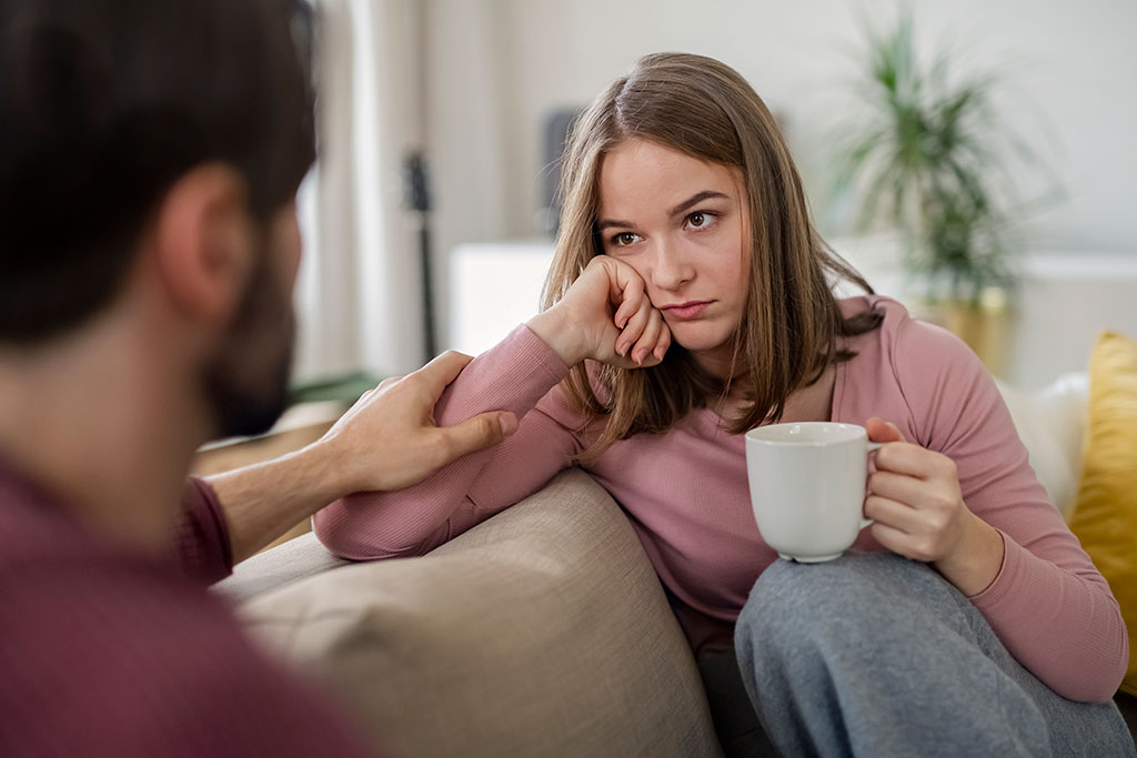 Dos personas mirándose de frente, conversando, sin emociones en sus rostros.