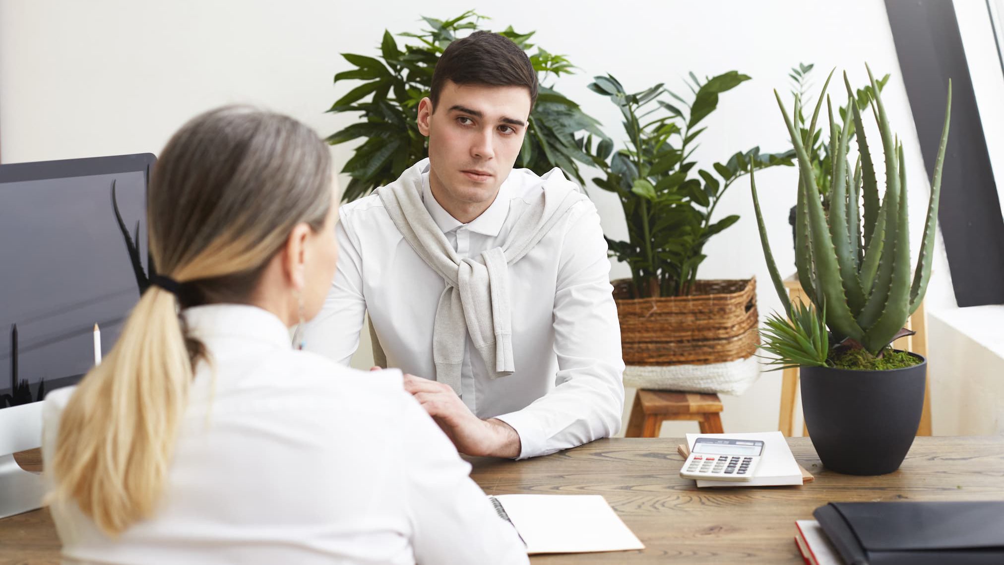 Dos personas conversando en una entrevista de trabajo con currículums en una mesa de madera